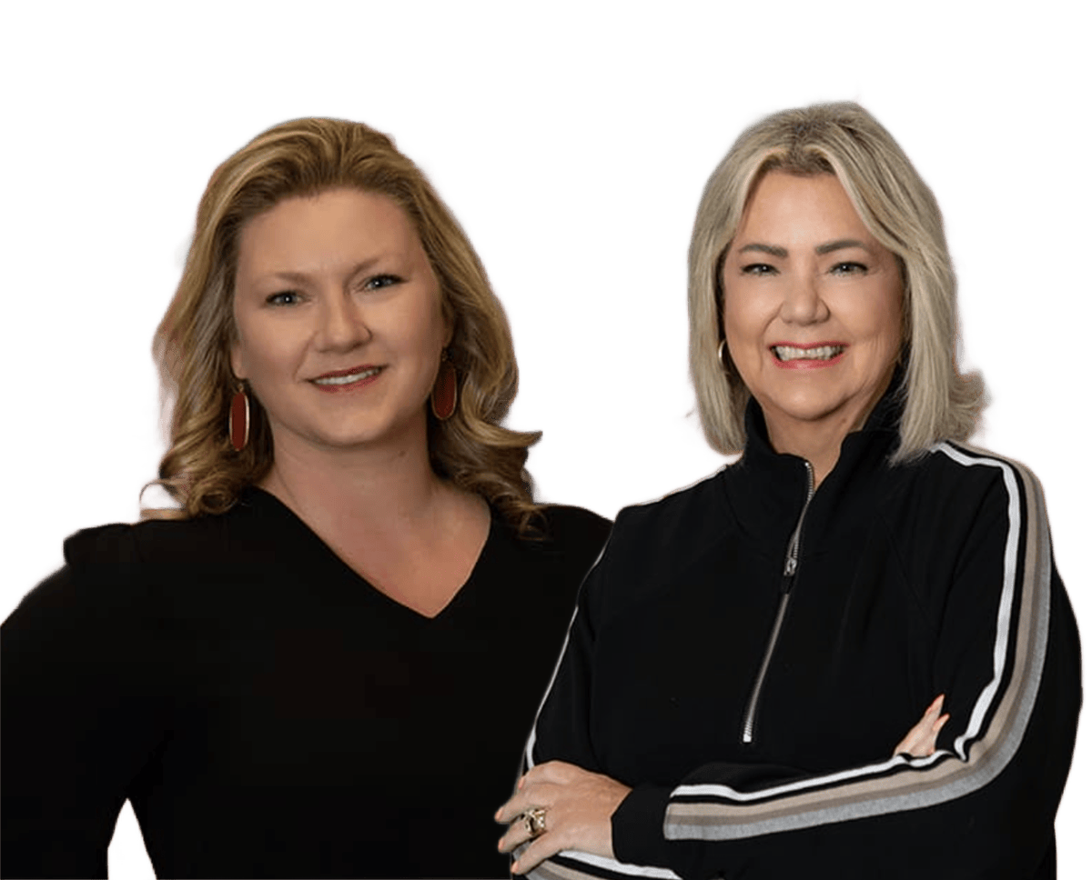 Two women smiling, standing side by side against a plain white background.
